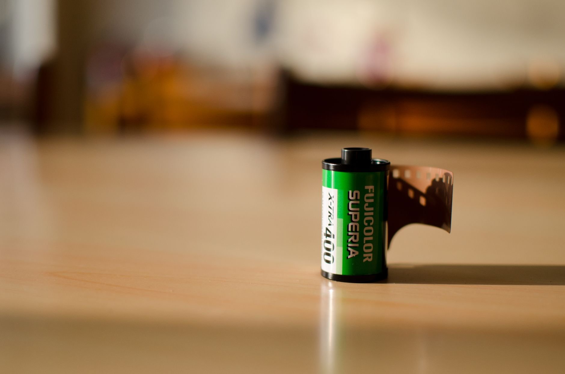 Close-up of Fujicolor Superia film roll on a wooden table in natural light.