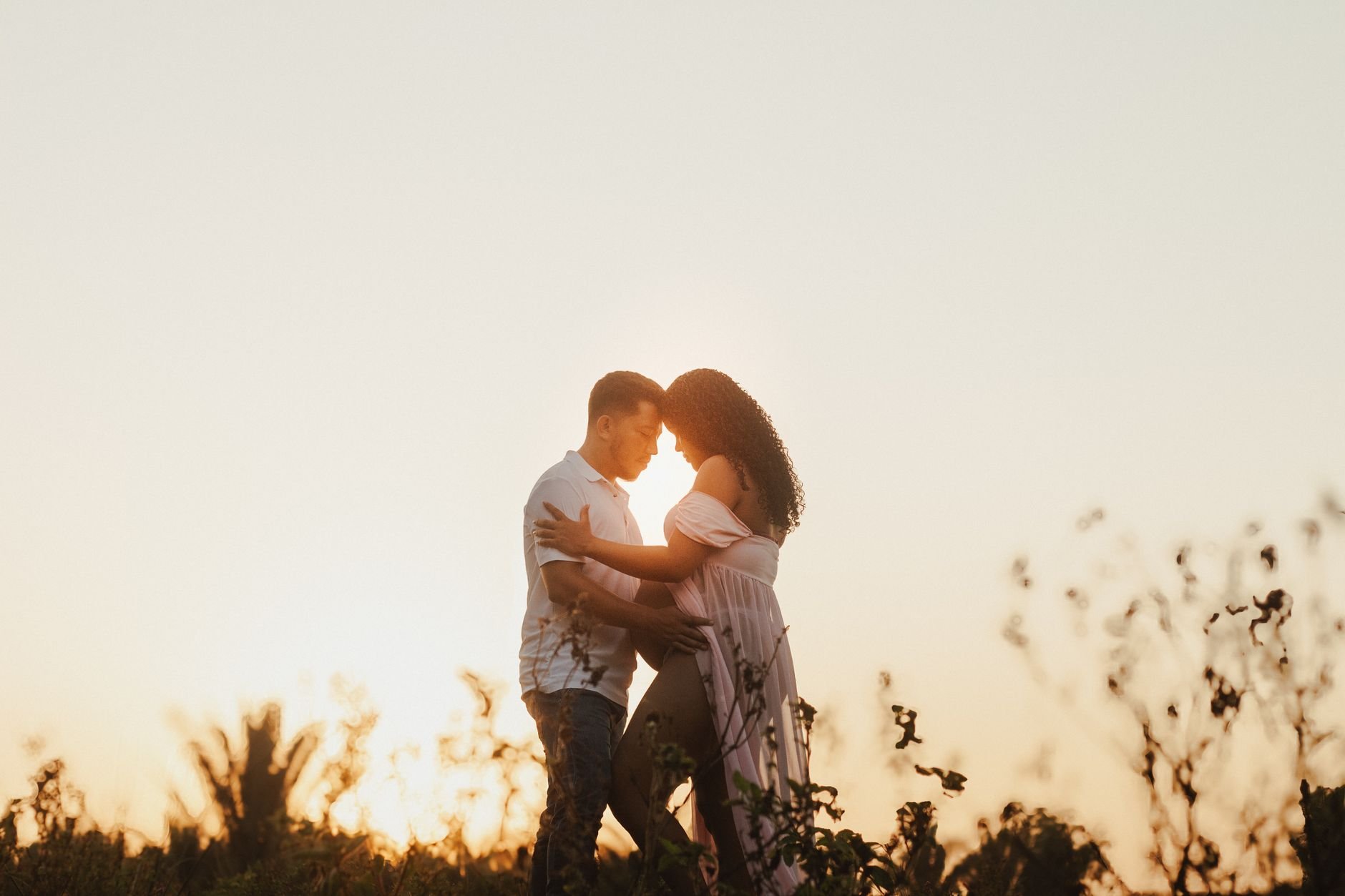 Couple embracing during a golden hour maternity shoot outdoors.